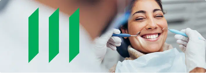 A smiling woman sits in a dental chair while a dentist holds dental tools near her mouth; Manulife logo appears on the left side of the image.